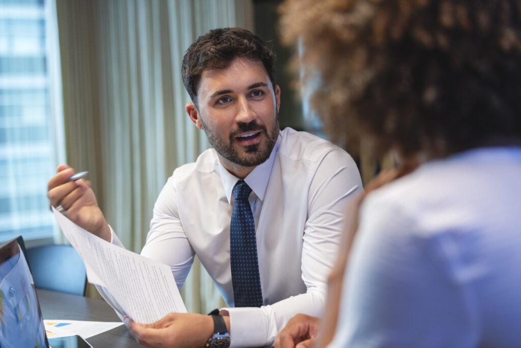 A lawyer talking to his client as he holds a document related to his client's case.