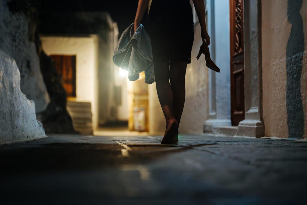 Woman walking barefoot at night on the streets.