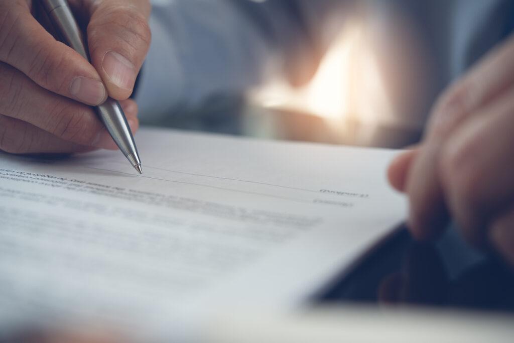 Man holding a pen while writing on a document.