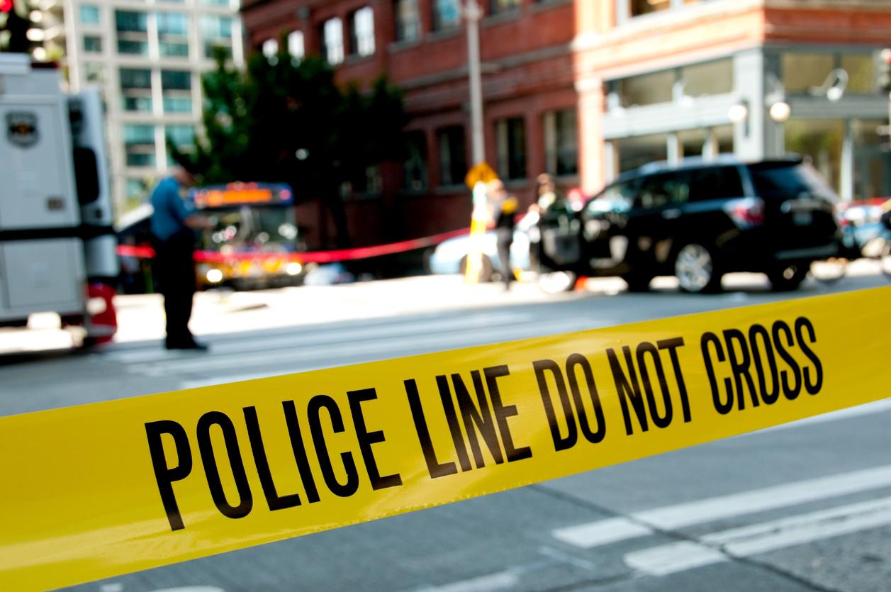Police line at a crime scene with unrecognizable officers in the background.
