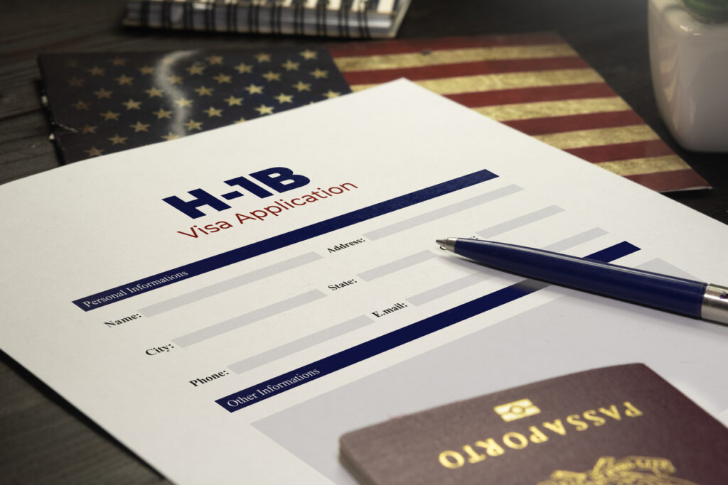 H1B visa application form with pen and passport on the table.